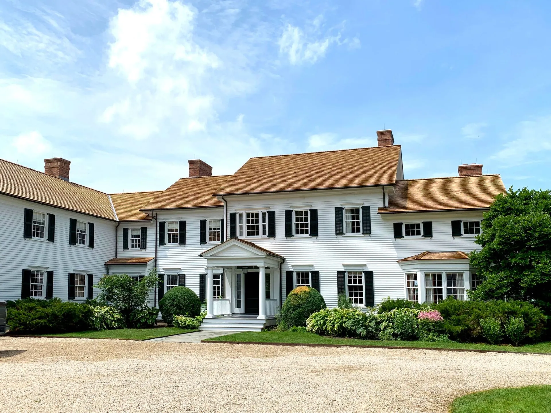 Front view of a classic white residence with a completed cedar roof